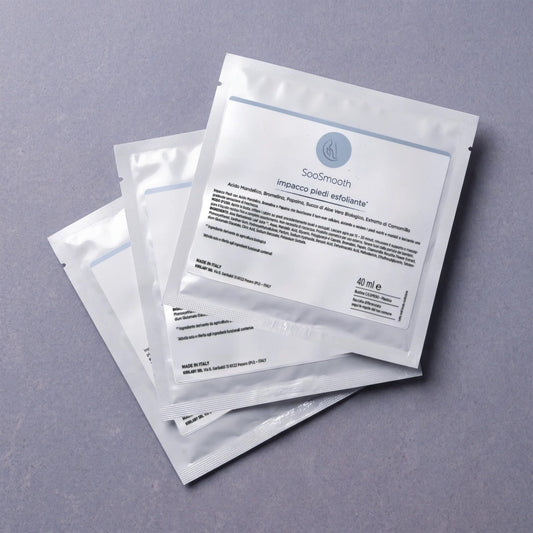 Impacco Piedi Esfoliante SooSmooth, tre bustine monouso su piano ardesia lilla