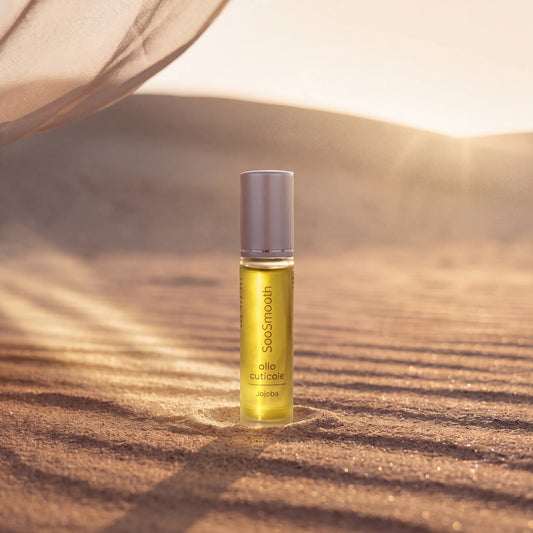 Roll-on Olio Cuticole Jojoba SooSmooth da 10 ml appoggiato sulla sabbia di una duna al tramonto