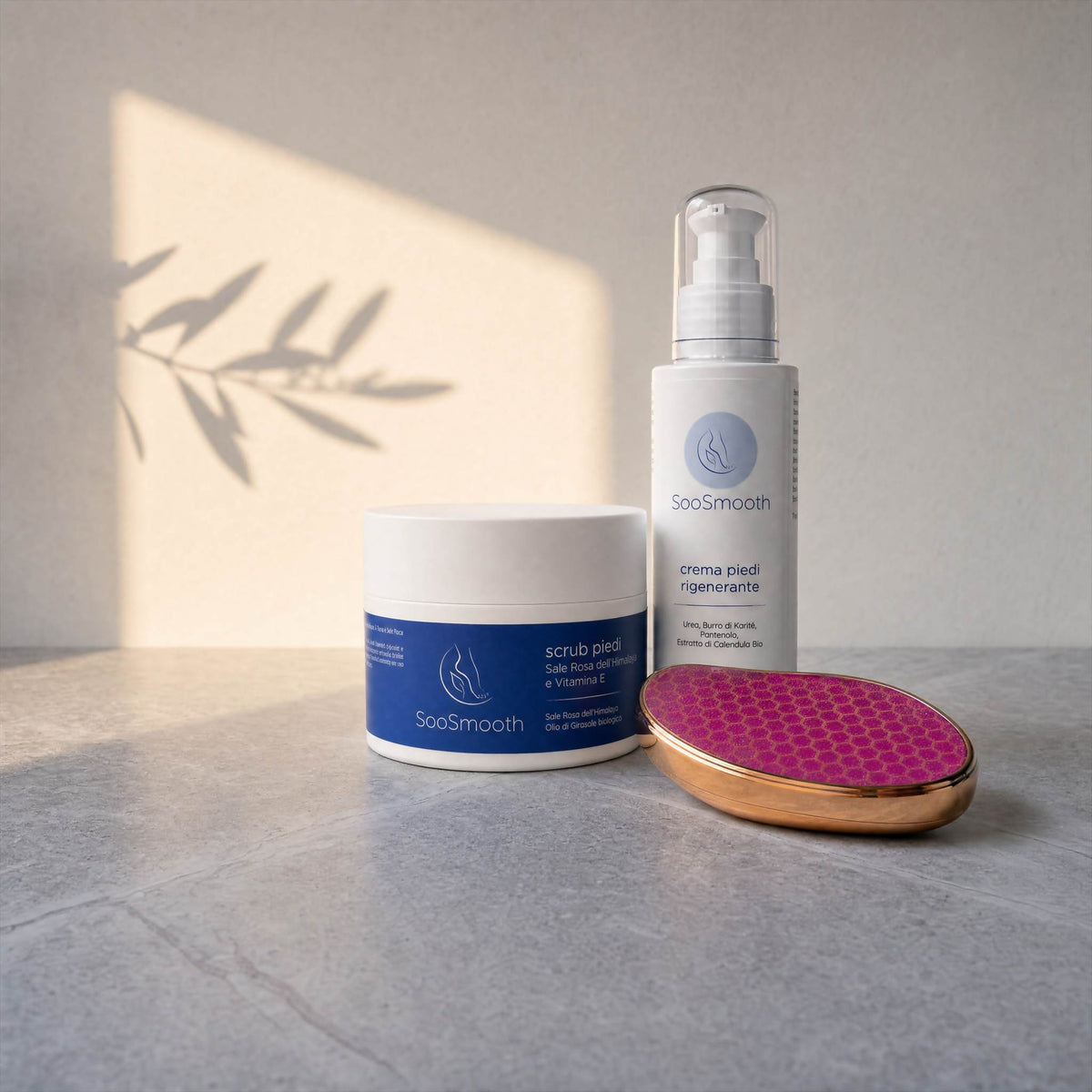 Kit Rituale di Seta SooSmooth livello Essenza, lima manuale in nano-vetro, scrub piedi al sale rosa dell'Himalaya e crema piedi rigenerante su un piano di pietra grigia